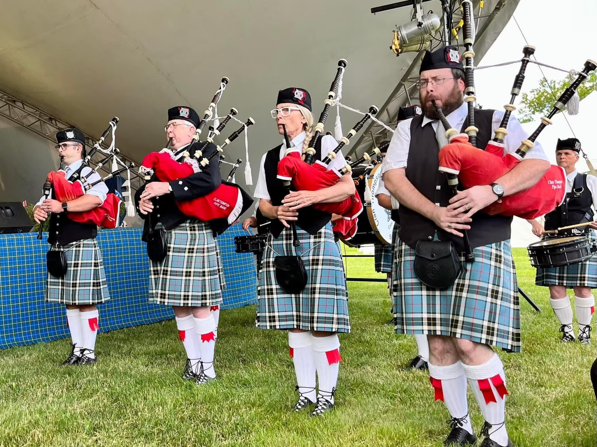 Clan Thompson Pipe Band performing under an outdoor canopy