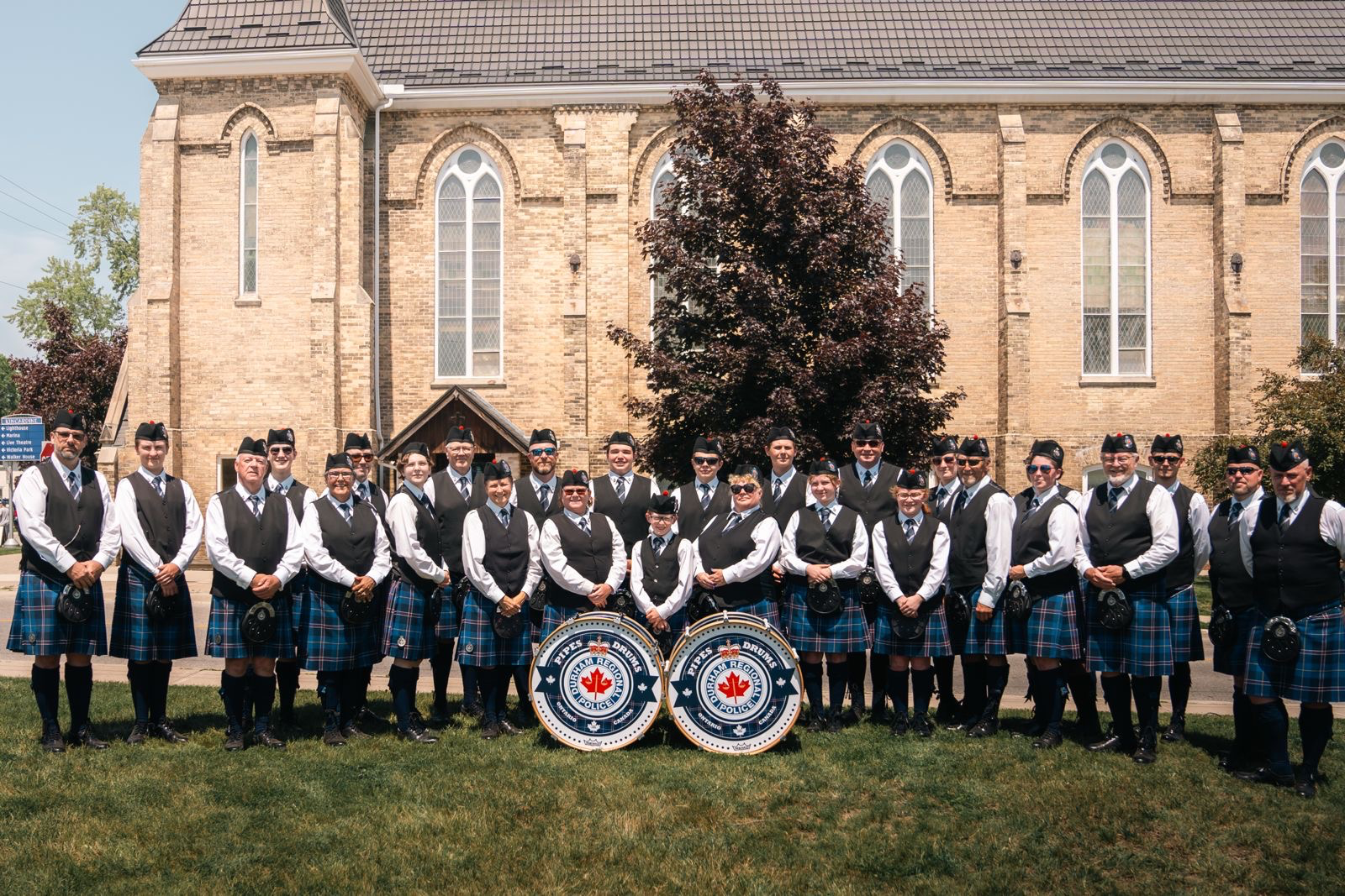 Durham Regional Police Pipes and Drums posing together with their bass drums