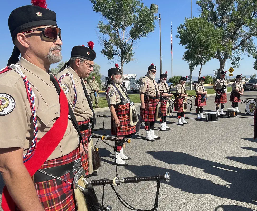 Members of the Pipes and Drums of the Black Devils standing outdoors with pipes and drums.