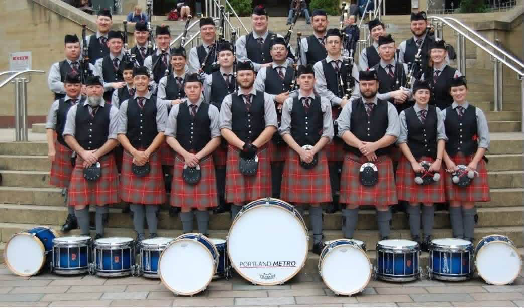 Portland Metro Pipe Band posed on steps with its drums