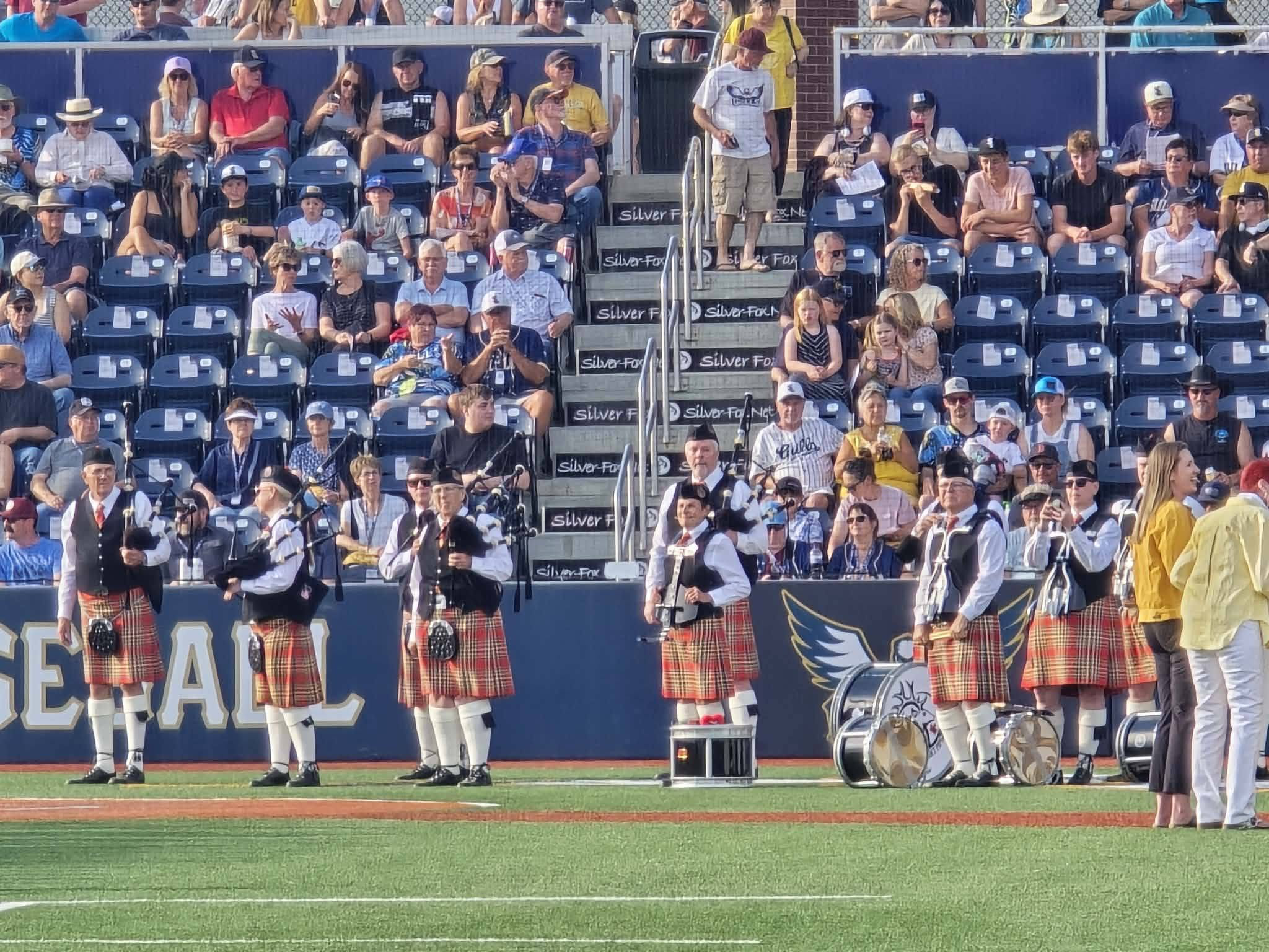 Red Deer and District Pipe Band performing at a baseball field
