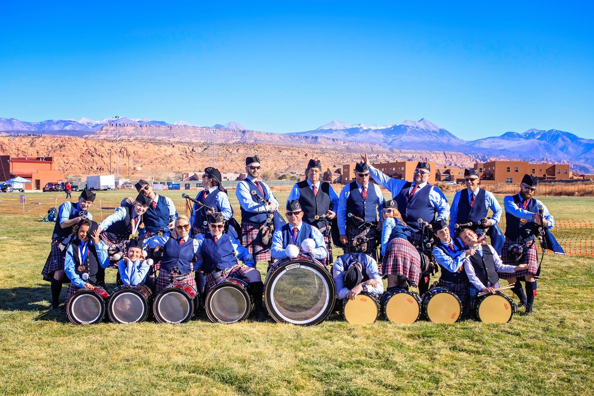 Salt Lake Scots pipers and drummers gathered outdoors with mountains behind them